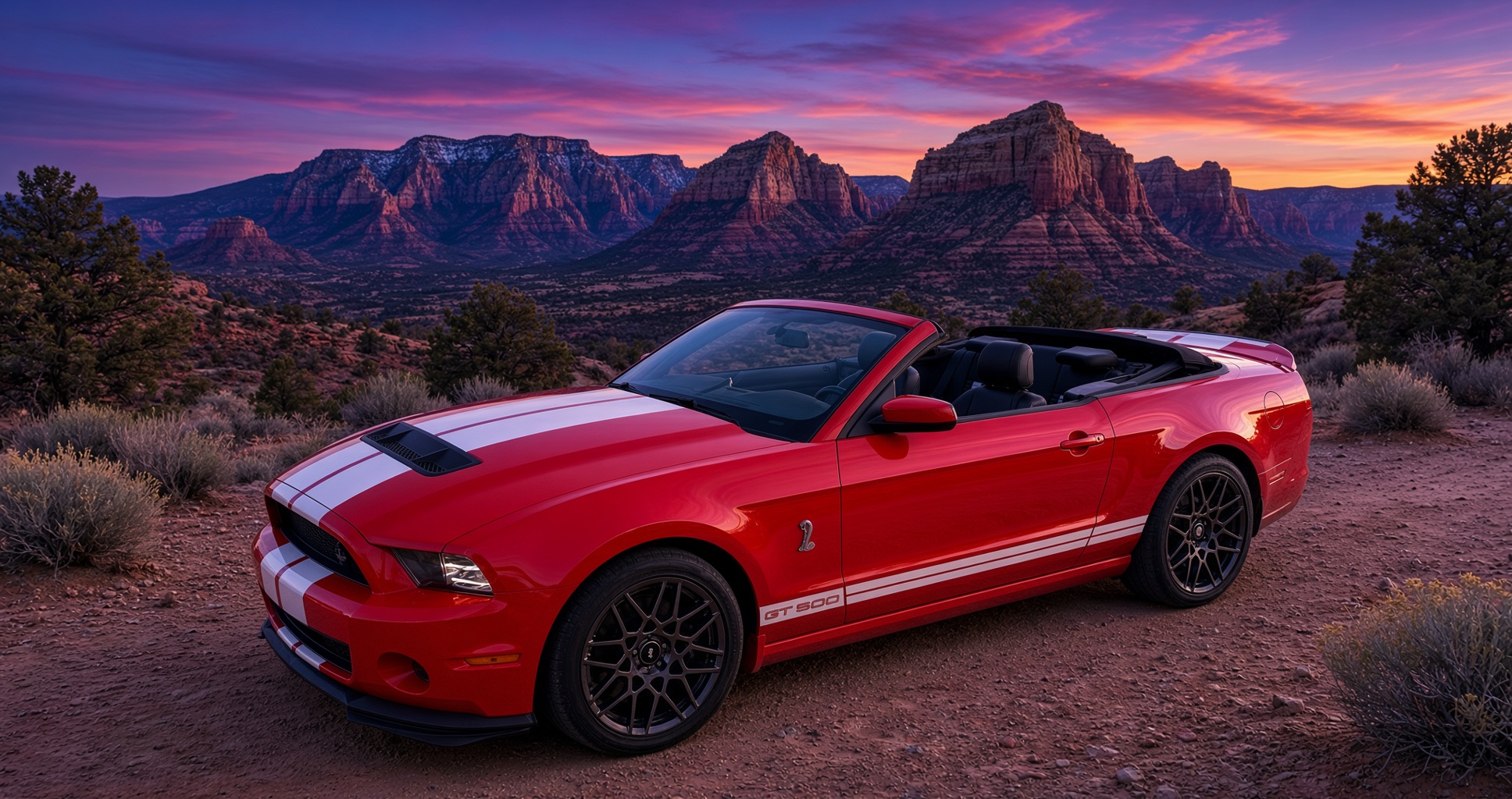 Kenny LeMans, a Race Red 2014 Shelby GT500 convertible, parked on red earth at dusk with the Sedona rocks behind him.
